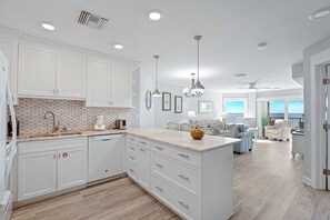 A modern kitchen with white cabinetry, a central island, and a dining area with a view.