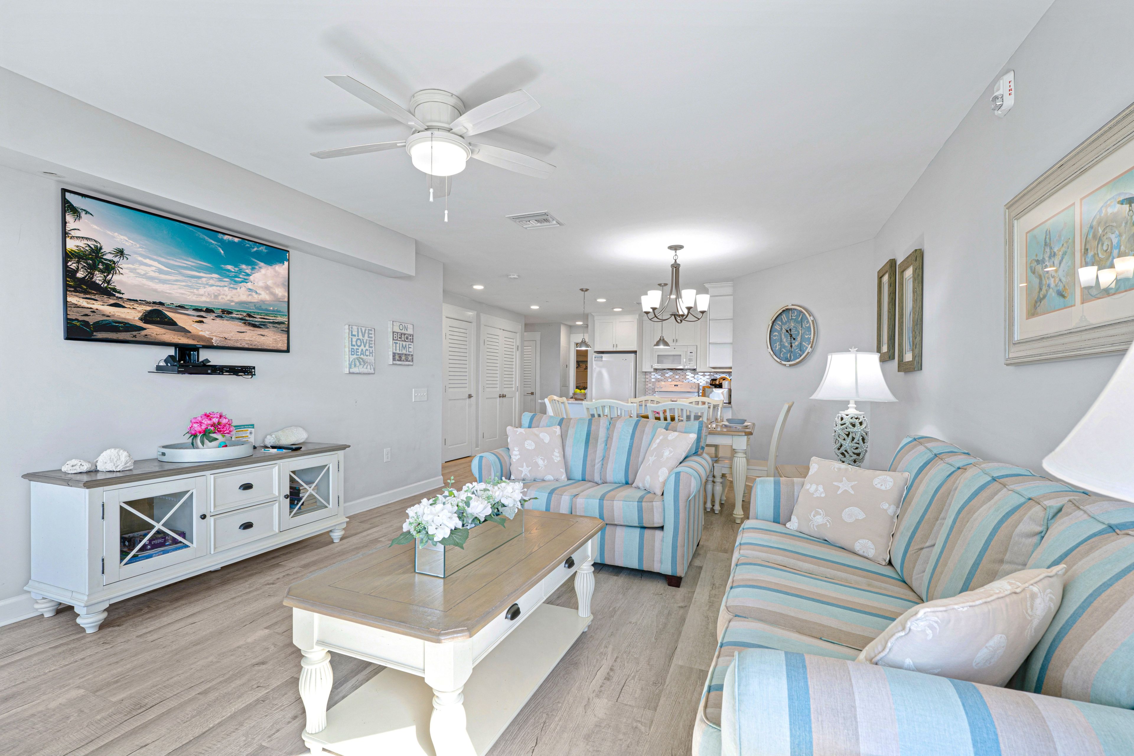 A living room with a television, sofa, coffee table, and a ceiling fan.