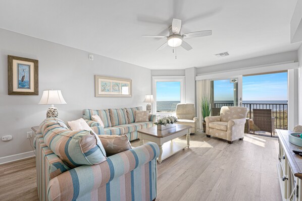 Large sliding doors open to a private balcony, filling the space with natural light and fresh sea breezes.
