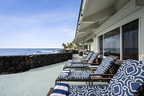 A beachfront lounge area with sun loungers and a stone wall.