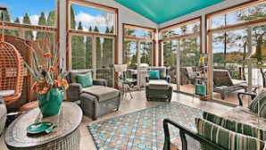 A sunroom with wicker furniture, a large window, and a ceiling fan.