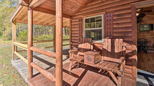 A wooden cabin with a porch, a window, and a television. - Parsons ‘Semper Fi’ Cabin w/ Fire Pit! (Parsons)