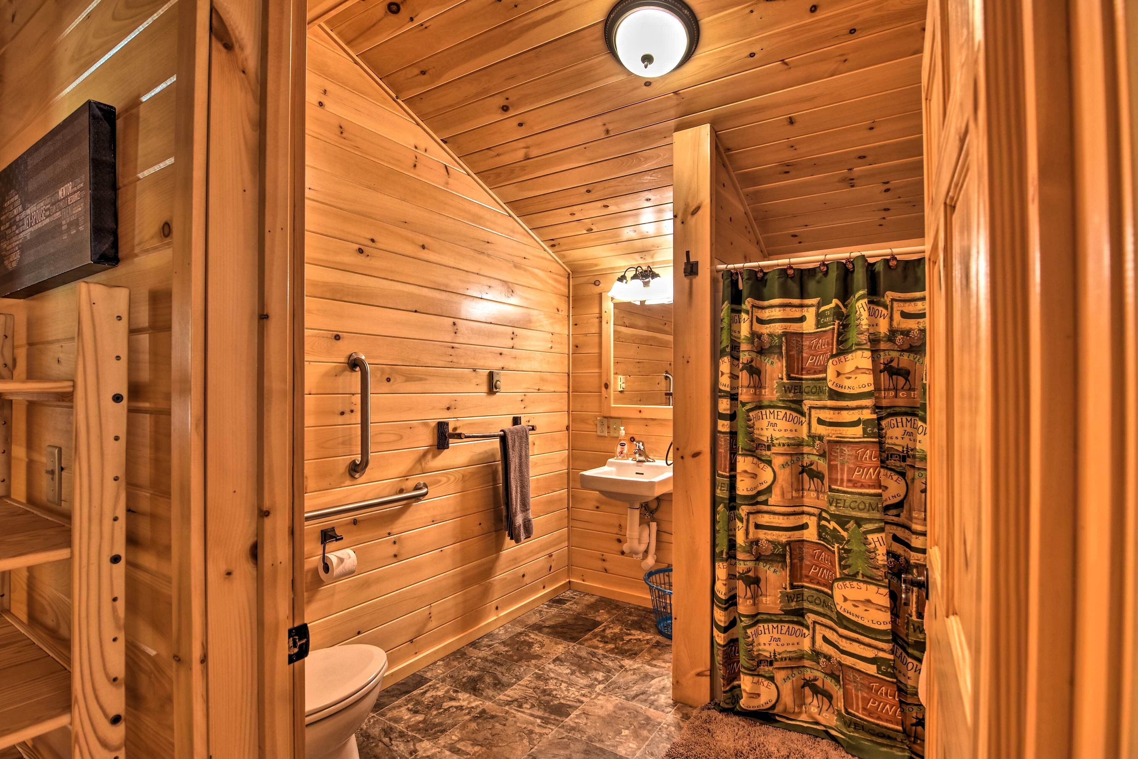 Une salle de bain rustique, aménagée dans une cabane en bois, comprenant des toilettes, un lavabo et un porte-serviettes.