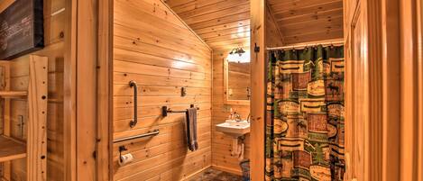 Une salle de bain rustique, aménagée dans une cabane en bois, comprenant des toilettes, un lavabo et un porte-serviettes.