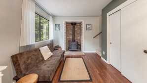 A cozy living room with a brown sofa, a wooden bench, a rug, and a fireplace.