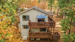 A two-story cabin with a balcony, surrounded by trees.