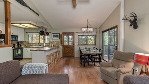 A spacious living area with a dining table, two sofas, and a chandelier.
