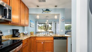 A modern kitchen with wooden cabinets, stainless steel appliances, and pendant lighting.