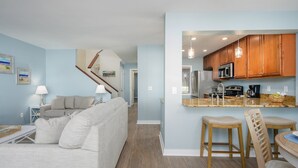 A modern living room with a sofa, a coffee table, and a kitchen area with wooden cabinets and a countertop.