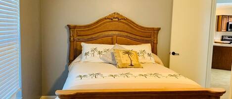 Een slaapkamer met een houten bed, een nachtkastje en een raam met jaloezieën.