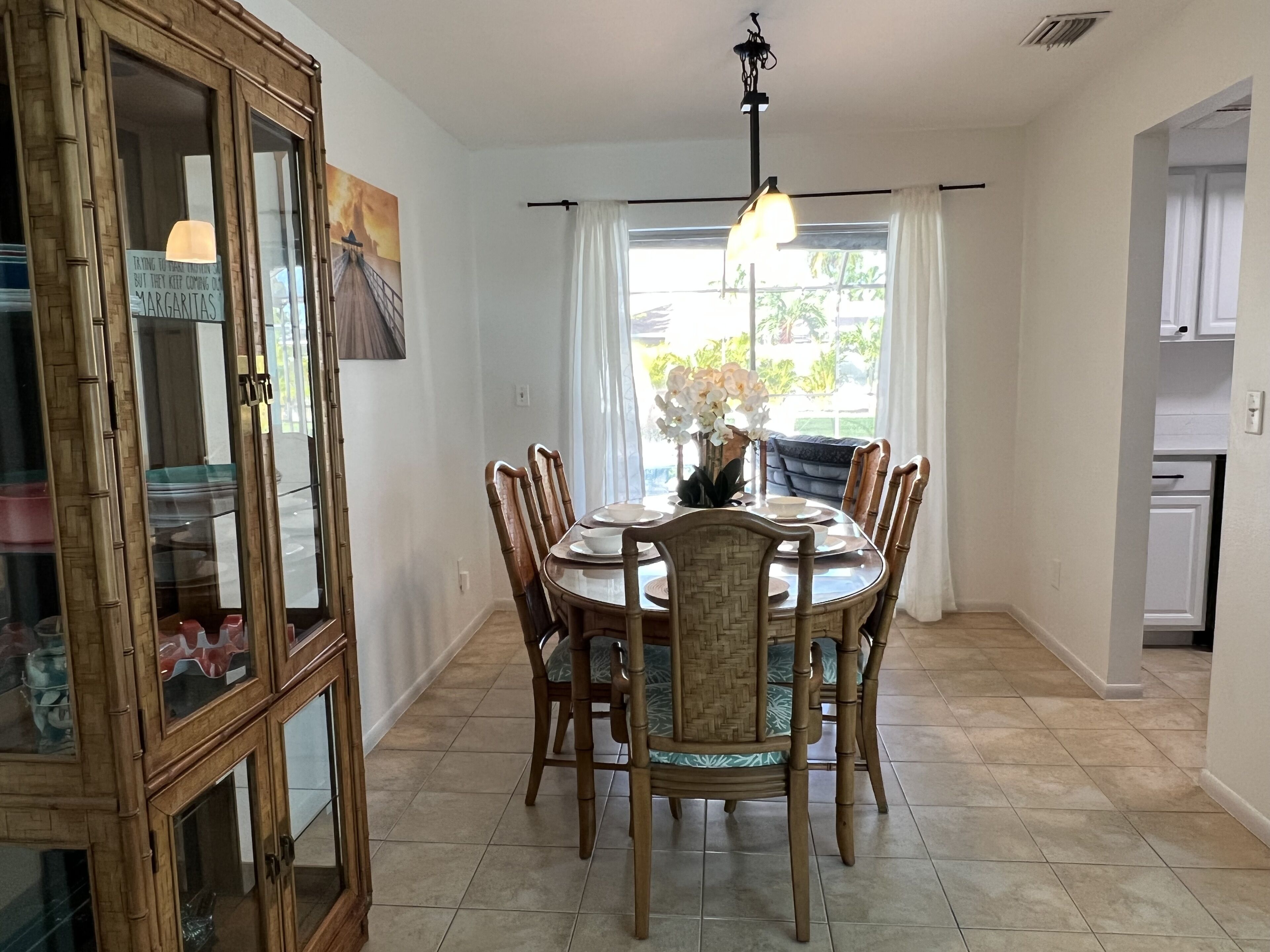 A dining area with a round table, six chairs, and a chandelier.