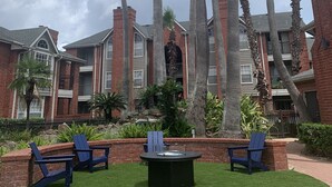 A courtyard with tall palm trees, brick buildings, and outdoor seating. - Brand New near Houston Medical Center / Rice University / NRG Stadium (Houston)