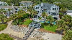 A large, multi-story beachfront property with a swimming pool, a dock, and a well-maintained lawn. - Luxury Family Oceanfront Oasis | Private Pool, Sun Decks w Views, Walkable to Coligny Plaza (Hilton Head Island)
