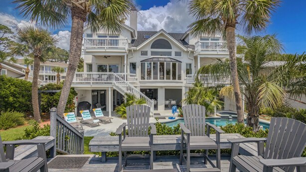 A large, multi-story house with a pool, surrounded by palm trees and outdoor seating. - Luxury Family Oceanfront Oasis | Private Pool, Sun Decks w Views, Walkable to Coligny Plaza (Hilton Head Island)