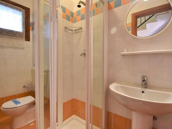 Un baño con inodoro, cabina de ducha y lavamanos.