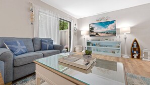 Una sala de estar con sofá, mesa de centro y televisor.