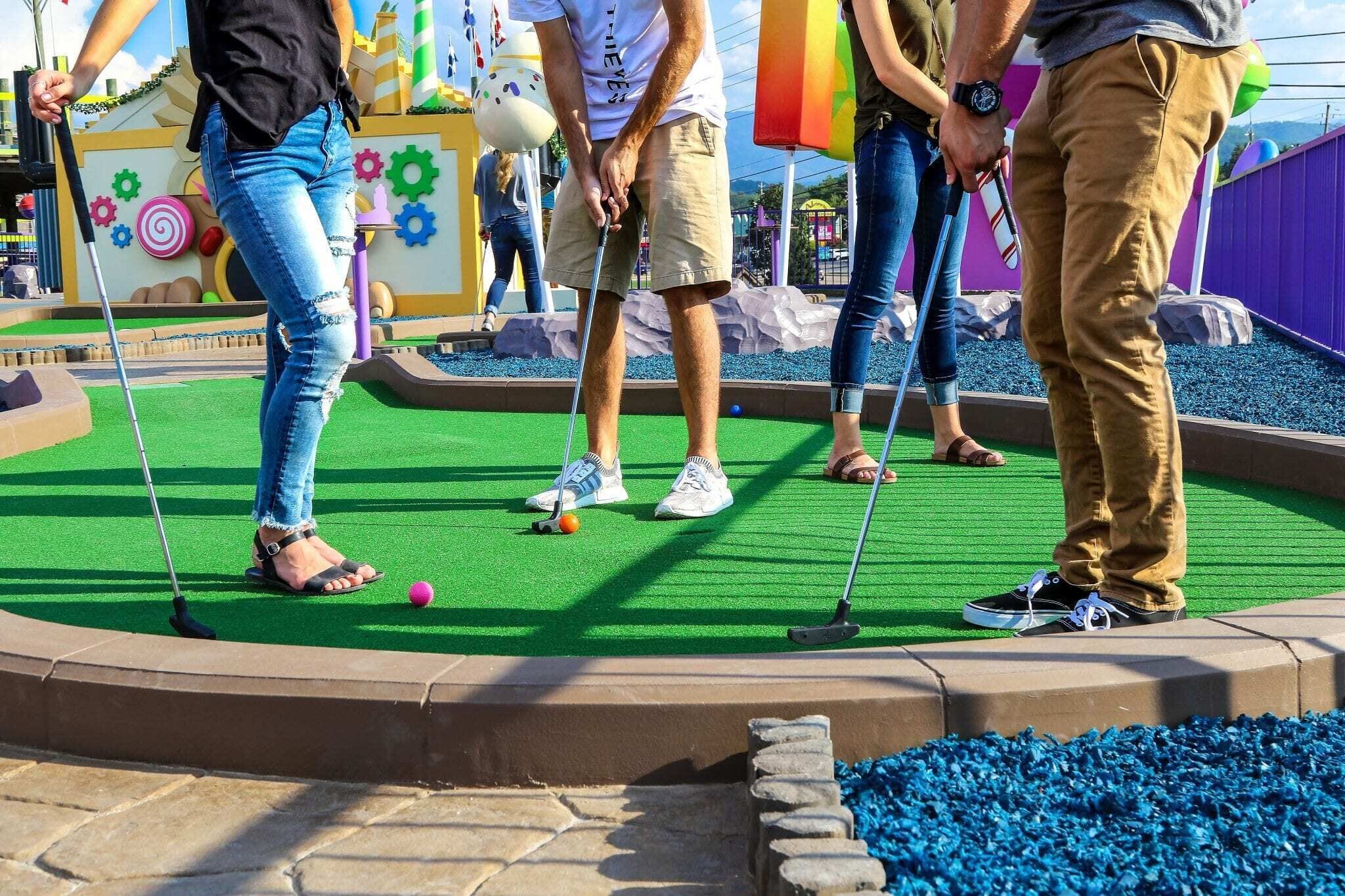 A miniature golf course with a green artificial turf, colorful decorations, and a variety of obstacles.