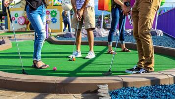A miniature golf course with a green artificial turf, colorful decorations, and a variety of obstacles.