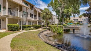 A multi-story hotel with balconies, a landscaped garden, and a pond with a fountain. - Renovated Forest Beach Villa | Walk to Beach & Coligny Plaza (Hilton Head Island)