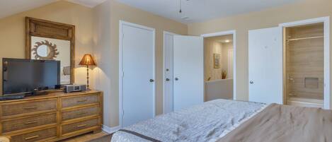 A bedroom with a bed, a dresser, a television, and a ceiling fan.