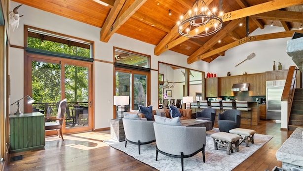 A spacious living area with a wooden ceiling, large windows, and a modern kitchen.