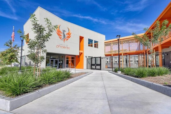 A modern building with a prominent Phoenix logo, a covered outdoor area, and a clear sky.