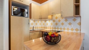 Una cucina moderna con mobili in legno, un'isola centrale con una ciotola di frutta e un rivestimento a mosaico a forma di diamante.