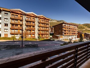 A multi-story hotel with balconies, stone facade, and a hilly backdrop.