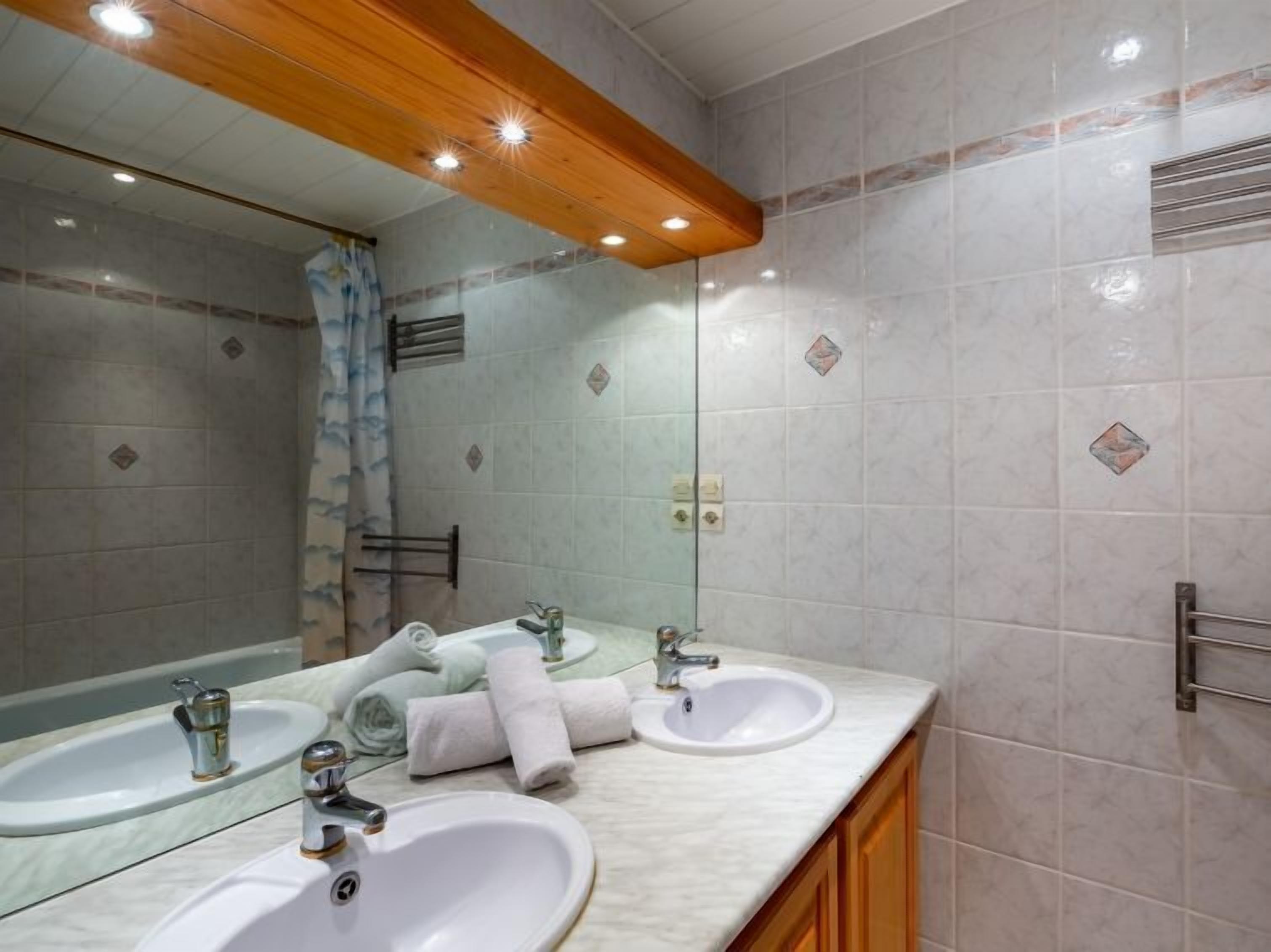 A bathroom with two sinks, a mirror, and a shower.