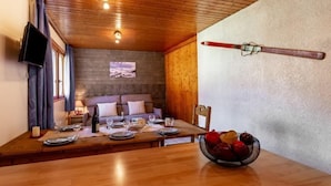 Un'accogliente sala da pranzo con un tavolo di legno apparecchiato per due persone, una ciotola di frutta e uno sciio appeso al muro.