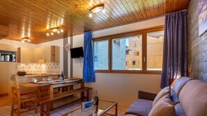Un soggiorno accogliente con soffitto in legno, un divano, un tavolino da caffè e un'area pranzo con tavolo e sedie.