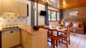 Una cucina accogliente con mobili in legno, forno integrato e zona pranzo con tavolo e sedie in legno.