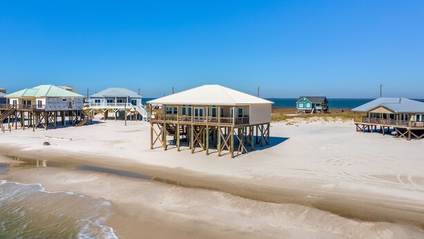 Una spiaggia con strutture in legno, tra cui un edificio principale e piccole cabine, il tutto rialzato su palafitte.