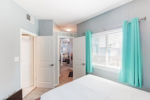 Comfortable retreat with a bed, window, and door to a separate room.
