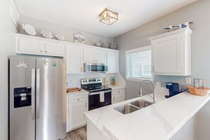 Enjoy cooking in this well-equipped kitchen with an oven, microwave, and stainless steel refrigerator.