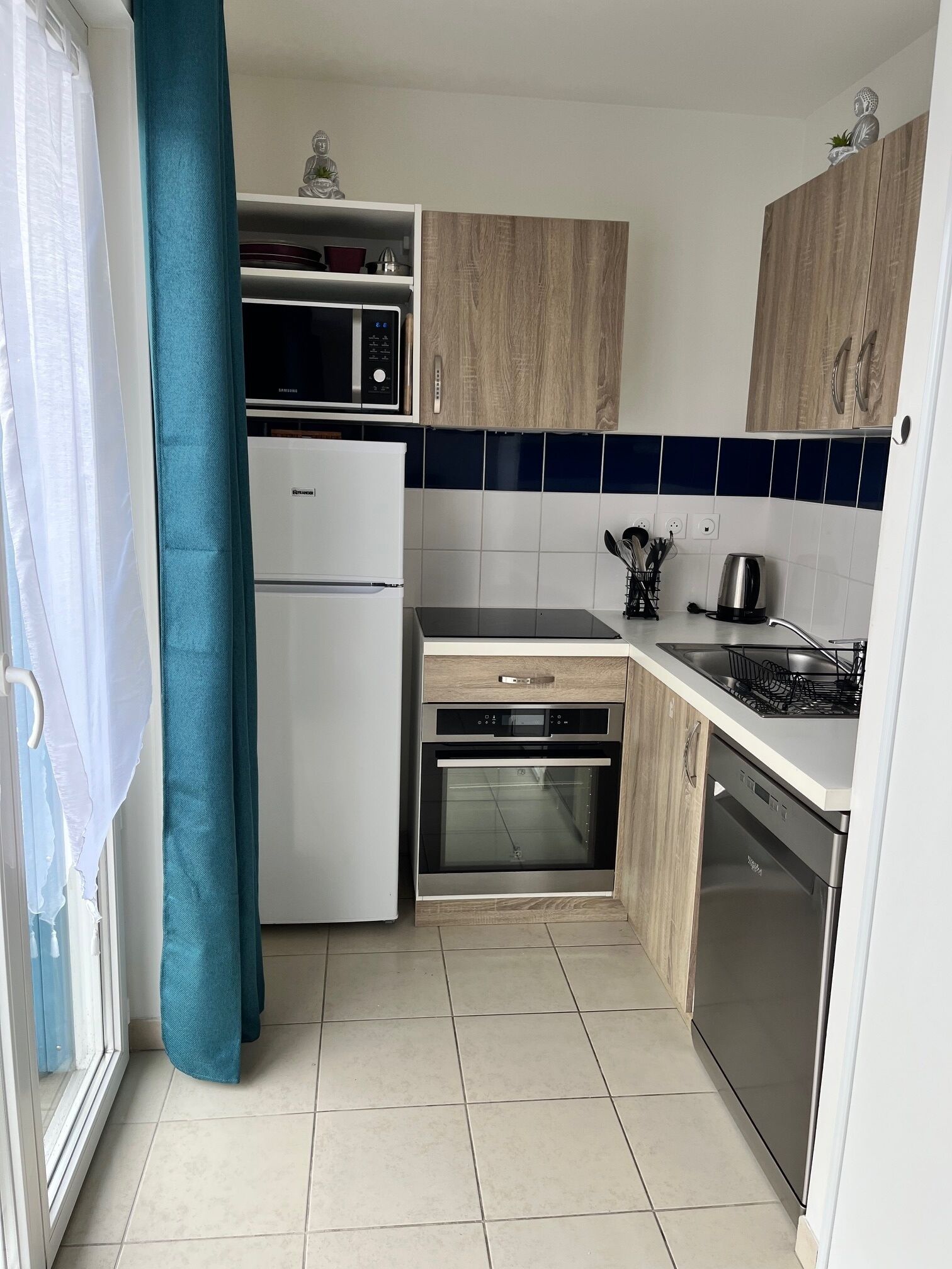 A compact kitchen with a refrigerator, microwave, oven, and dishwasher.