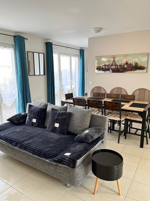 Una sala de estar moderna con un sofá, mesa de comedor, sillas y un cuadro en la pared.
