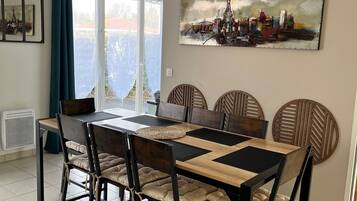 A dining area with a table set for six, surrounded by chairs with cushioned seats.