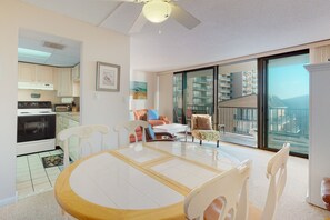 Enjoy meals in the dining area with a round table and comfortable chairs, surrounded by large windows offering a view of the balcony and cityscape.