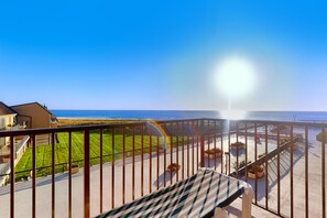 Enjoy the serene beachfront view from this balcony with a comfortable bench.