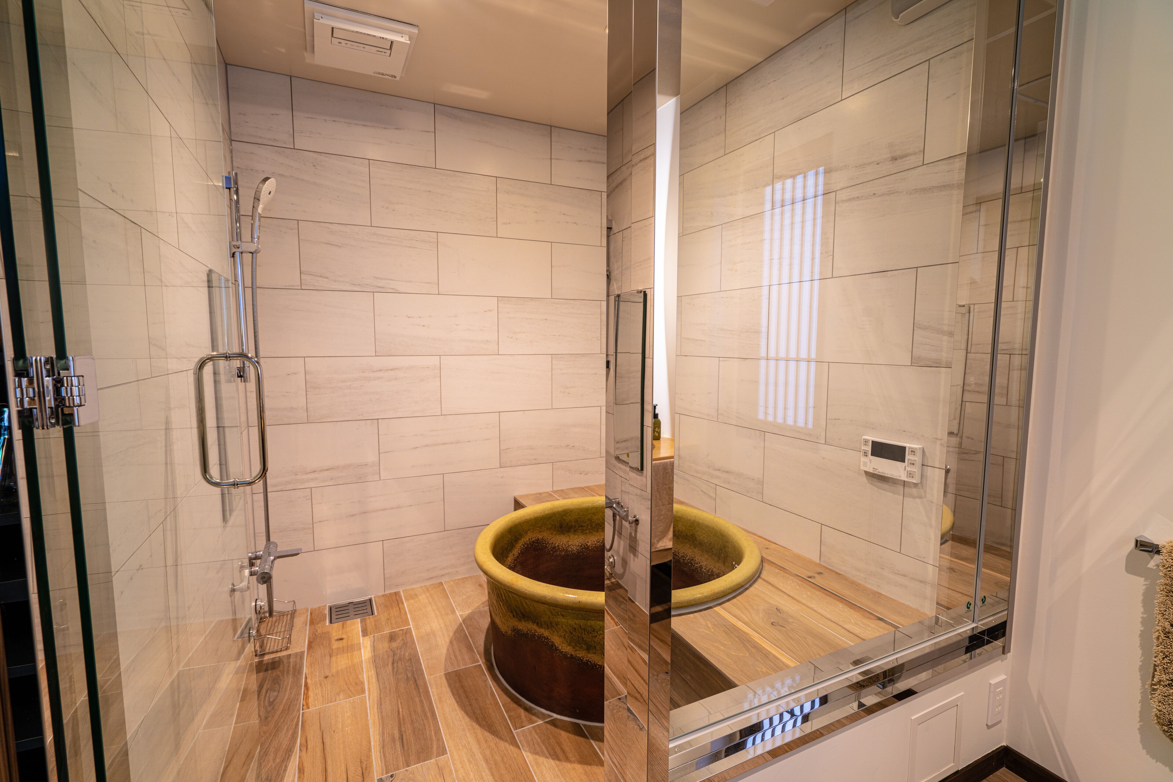 Un baño moderno con ducha de vidrio, suelo de madera y una bañera grande.