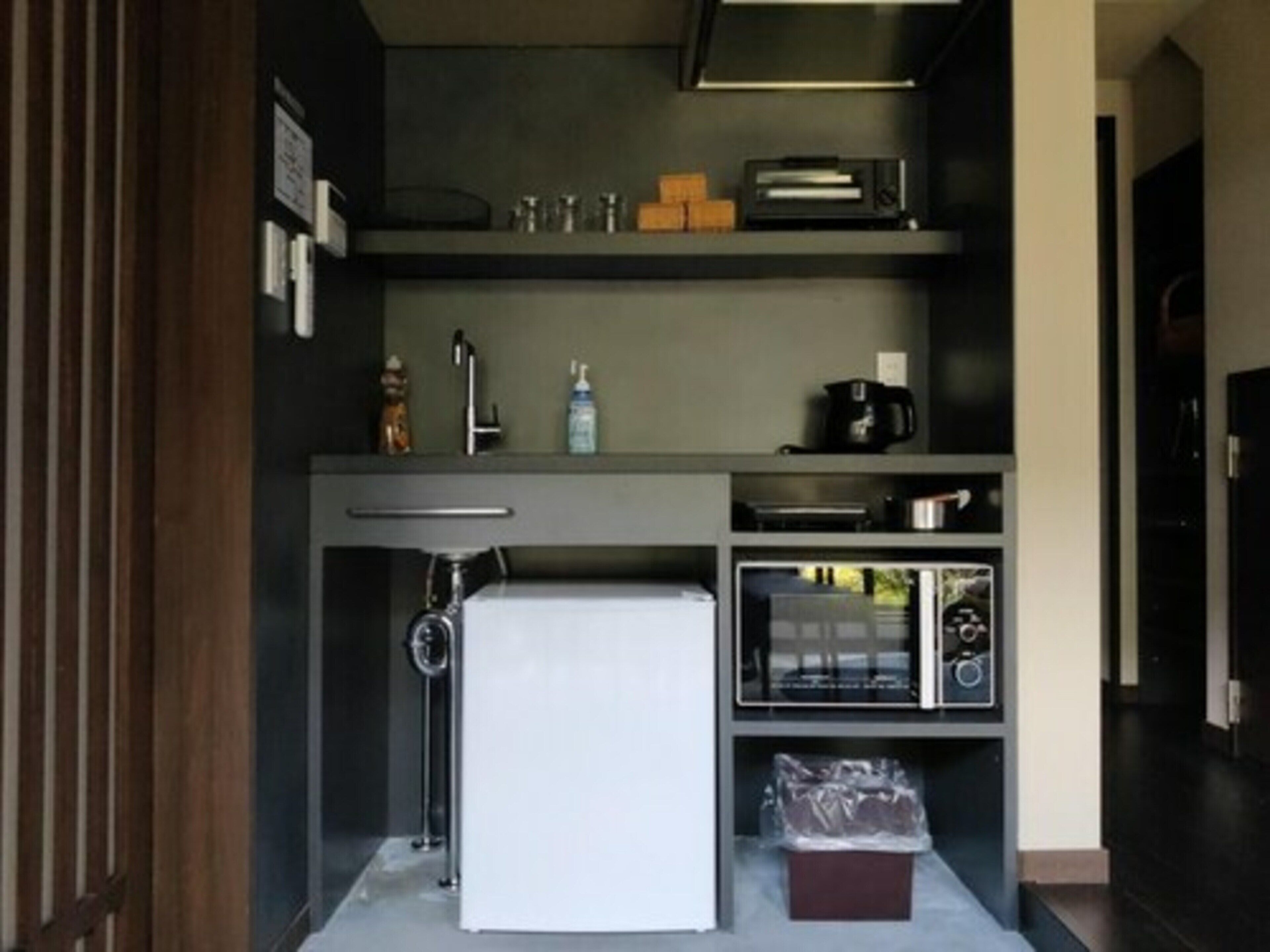 A compact kitchenette with a refrigerator, microwave, and coffee maker.
