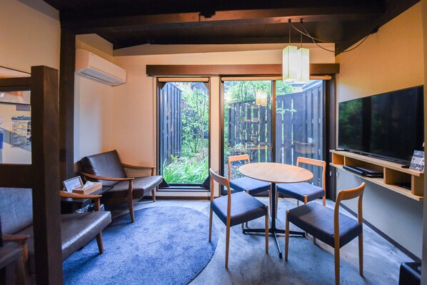A modern living room with a sofa, chairs, a round table, and a TV.