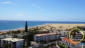 Et kysthotel med flere etager, en swimmingpool og udsigt til stranden og havet.