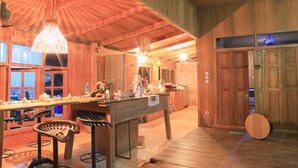Eine rustikale Küche mit Holzwänden, einer Bar inklusive Sitzhocker und einem großen Fenster, das für natürliches Licht sorgt.
