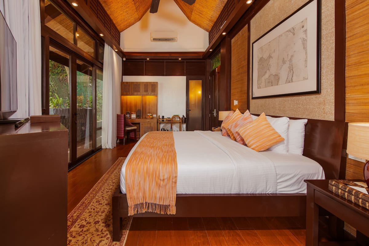 A spacious bedroom with a large bed, a desk, and a view of the outdoors.