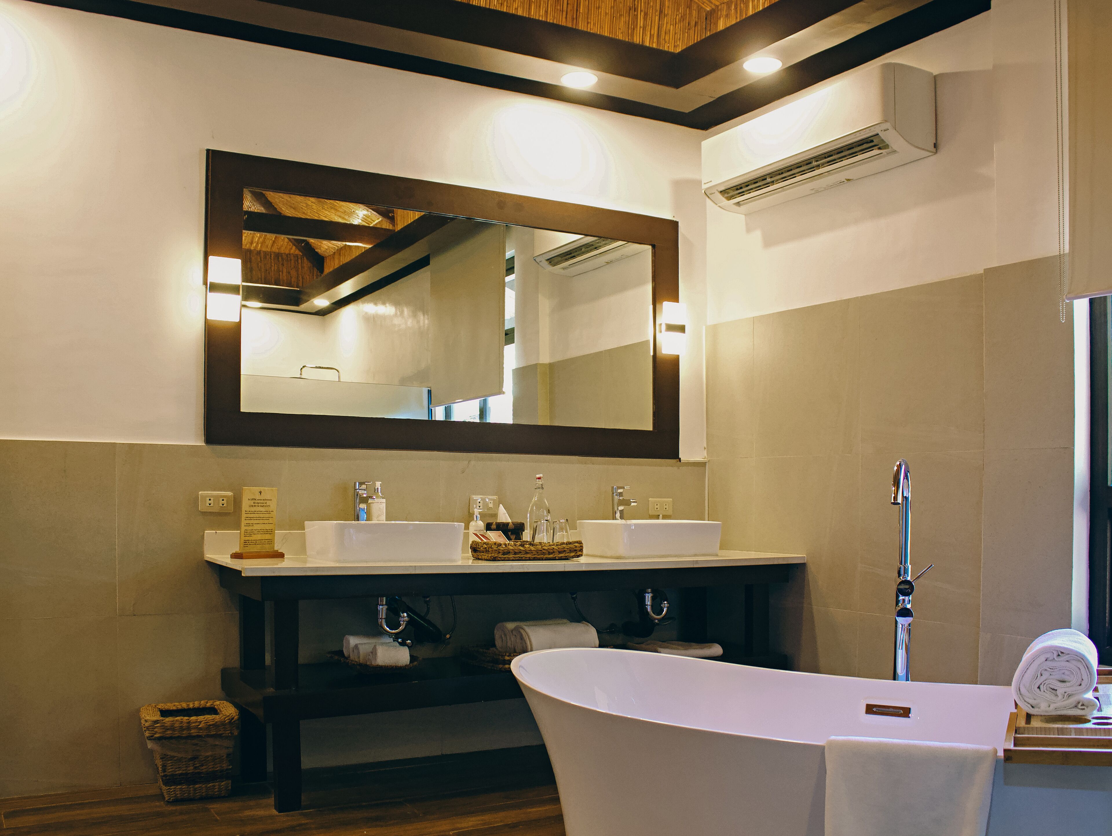 A bathroom with a large mirror, two sinks, a bathtub, and a towel rack.