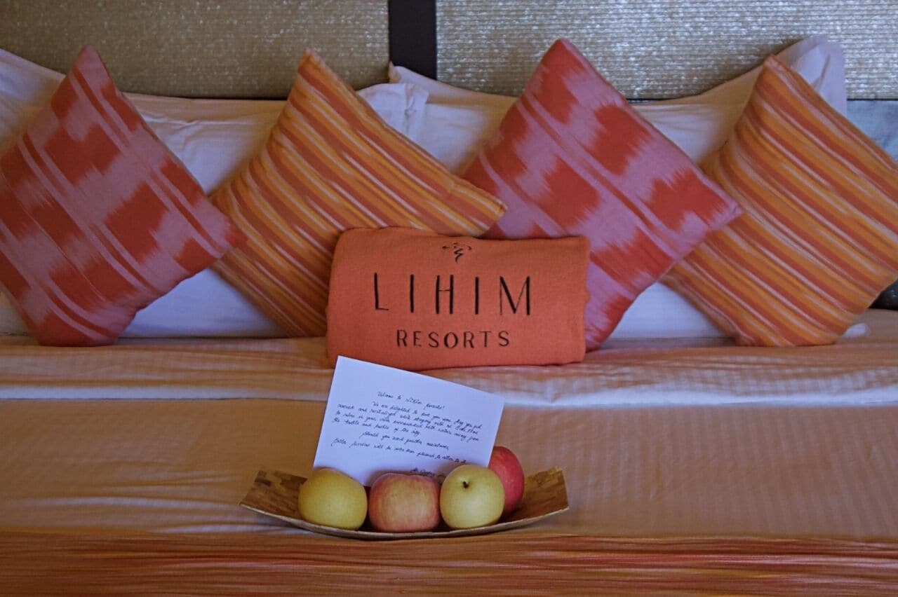 Una cama con un cojín que dice 'LIHIM RESORTS' y una nota encima.