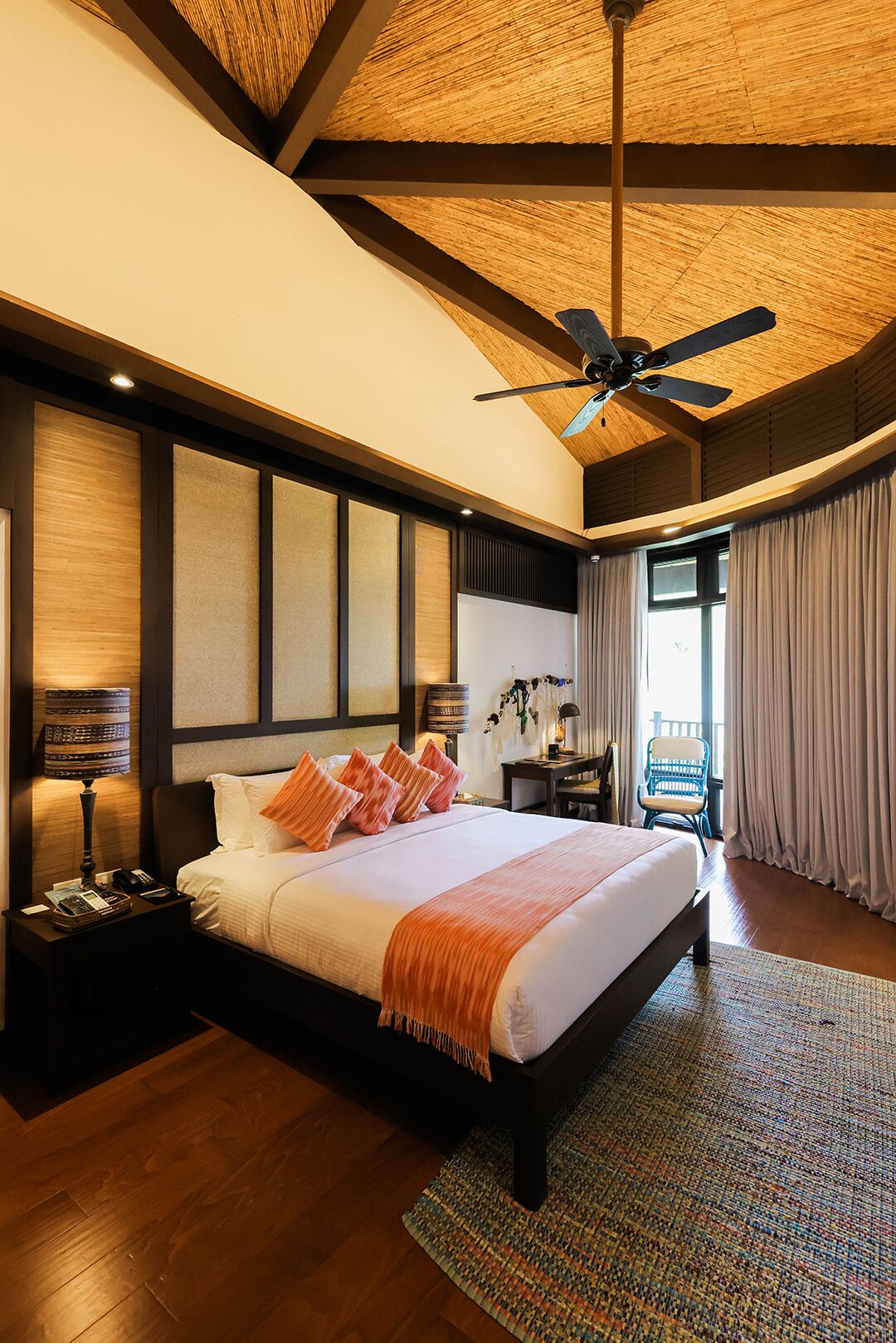 Un dormitorio amplio con una cama grande, ventilador de techo y vistas al exterior.