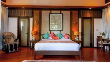 A spacious bedroom with a large bed, a massage chair, a dining table, and a framed picture on the wall.